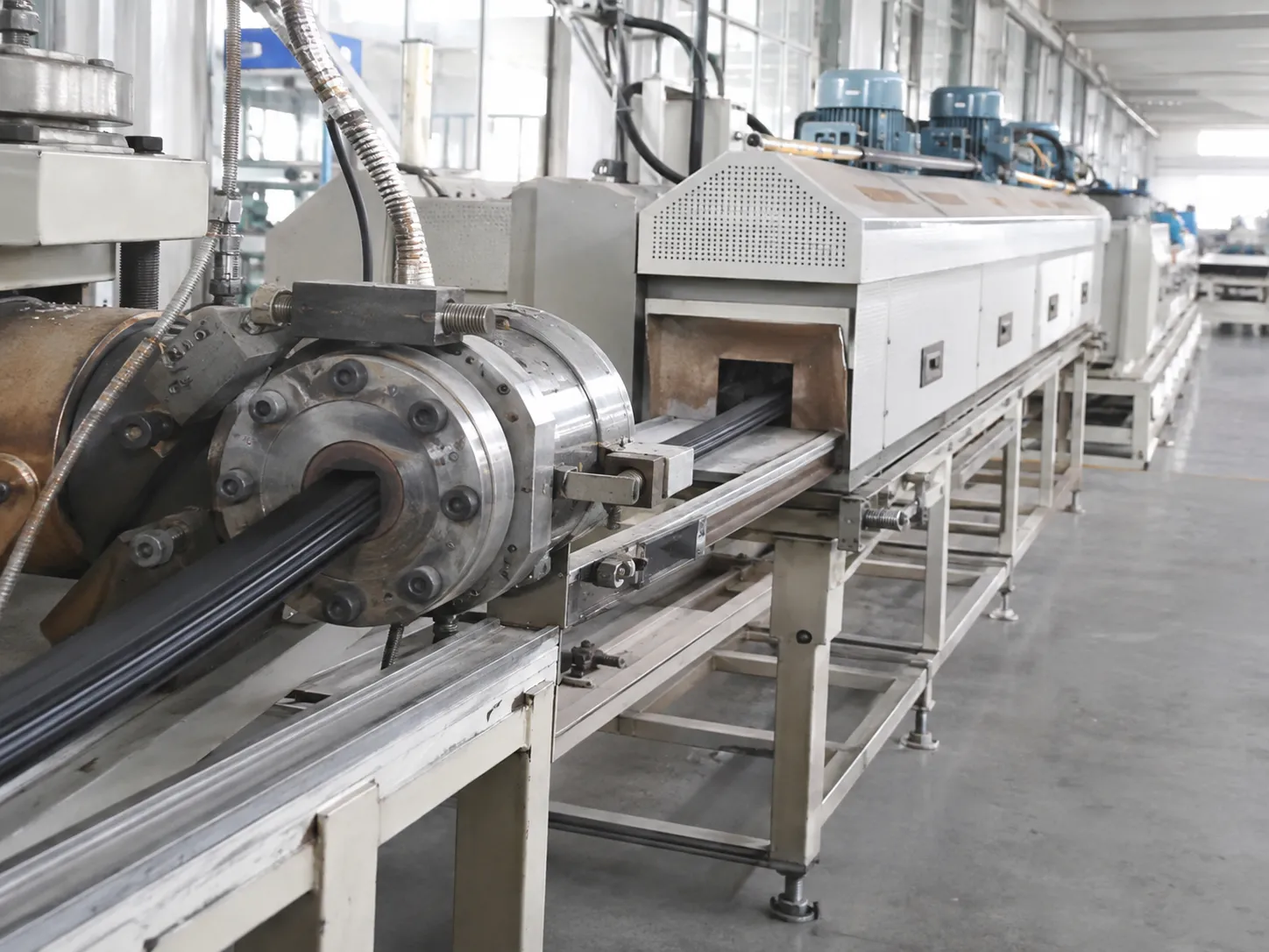 Rubber extruder die forming stage with profile entering continuous vulcanization line