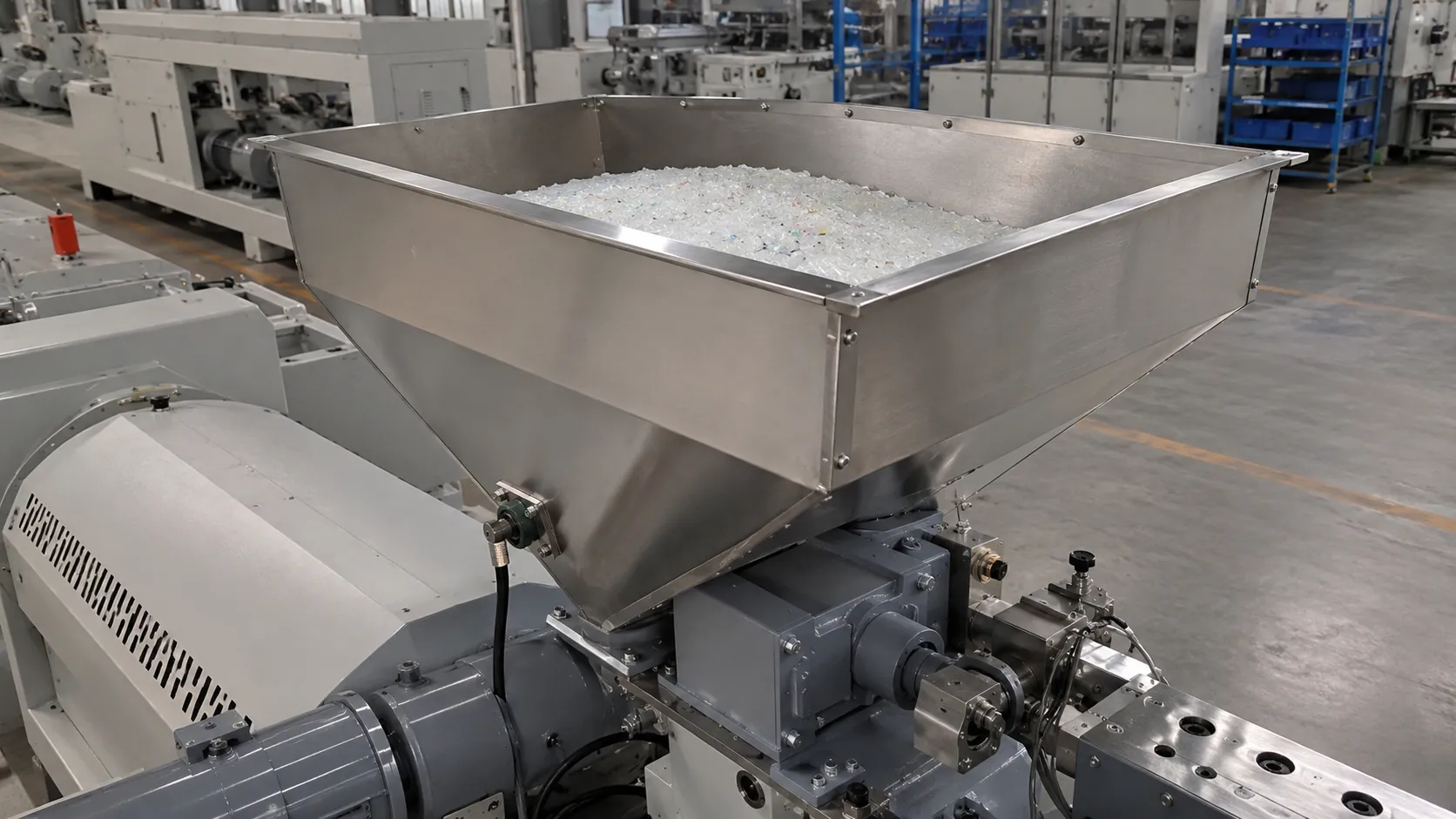 Stainless steel forced feed hopper loaded with recycled plastic pellets on UET recycling extruder